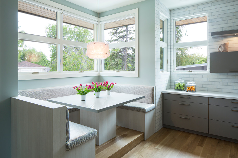 Moderne Wohnküche in L-Form mit flächenbündigen Schrankfronten, Küchenrückwand in Grau, braunem Holzboden, grauen Schränken, Kücheninsel und Unterbauwaschbecken in Salt Lake City