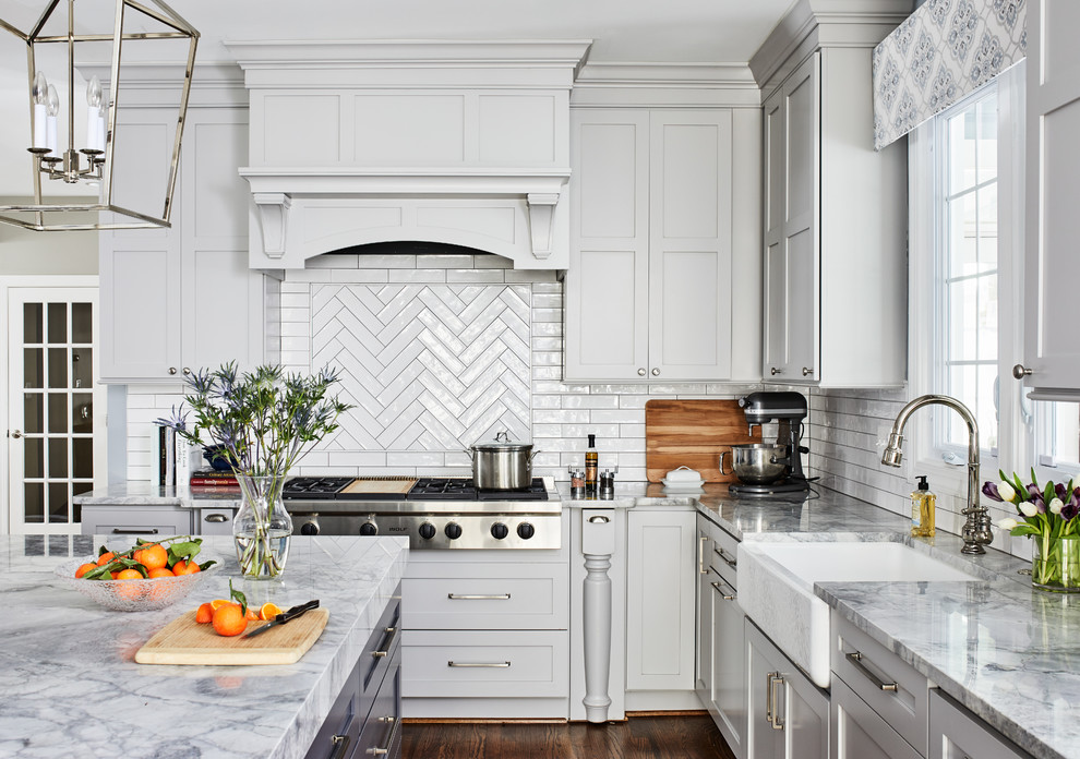 Inspiration for a large transitional l-shaped medium tone wood floor and brown floor eat-in kitchen remodel in Chicago with a farmhouse sink, shaker cabinets, gray cabinets, quartzite countertops, gray backsplash, porcelain backsplash, stainless steel appliances, an island and gray countertops
