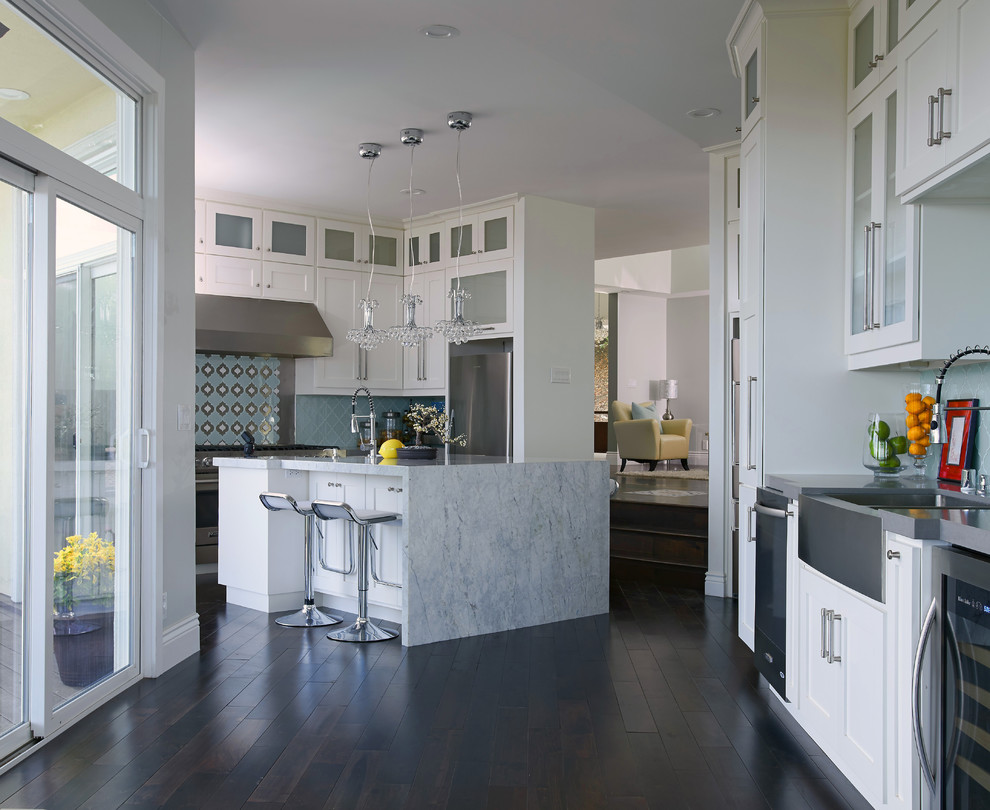 Design ideas for a traditional kitchen in San Francisco with a belfast sink, shaker cabinets, white cabinets, blue splashback, stainless steel appliances, dark hardwood flooring and an island.