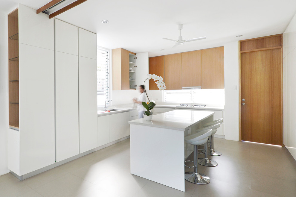 Bild på ett mellanstort funkis vit vitt kök, med släta luckor, bänkskiva i kvartsit, en köksö, grått golv, en undermonterad diskho, vita skåp, fönster som stänkskydd, vita vitvaror och skiffergolv