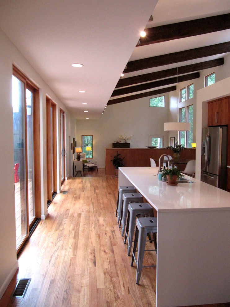 Пример оригинального дизайна: кухня-гостиная в стиле модернизм с техникой из нержавеющей стали, паркетным полом среднего тона и островом