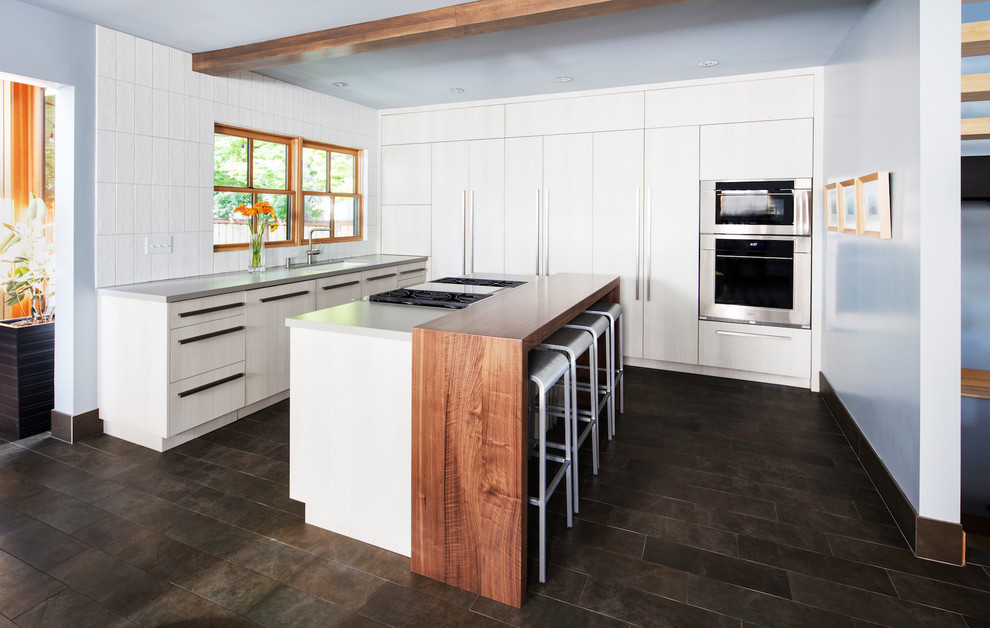 Eat-in kitchen - mid-sized contemporary u-shaped ceramic tile and brown floor eat-in kitchen idea in Salt Lake City with flat-panel cabinets, white cabinets, white backsplash, ceramic backsplash, stainless steel appliances, an island, an undermount sink, quartz countertops and white countertops
