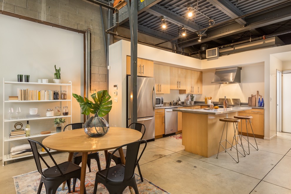 Immagine di una cucina industriale con ante lisce, ante in legno chiaro, elettrodomestici in acciaio inossidabile, pavimento in cemento, pavimento grigio e top grigio