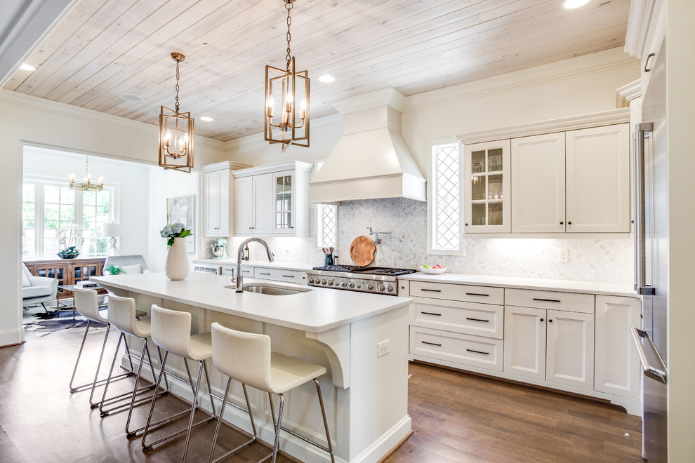 Exempel på ett klassiskt vit vitt kök med öppen planlösning, med en undermonterad diskho, luckor med infälld panel, vita skåp, flerfärgad stänkskydd, rostfria vitvaror, mellanmörkt trägolv, en köksö och brunt golv