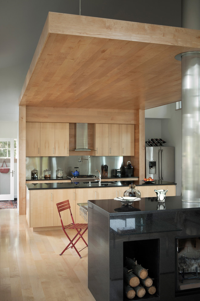 This is an example of a contemporary galley kitchen in Portland Maine with a submerged sink, flat-panel cabinets, light wood cabinets, metallic splashback, metal splashback and stainless steel appliances.