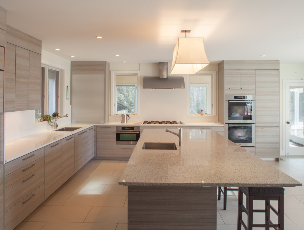 Example of a large trendy l-shaped kitchen design in Boston with a single-bowl sink, flat-panel cabinets, light wood cabinets, stainless steel appliances and an island