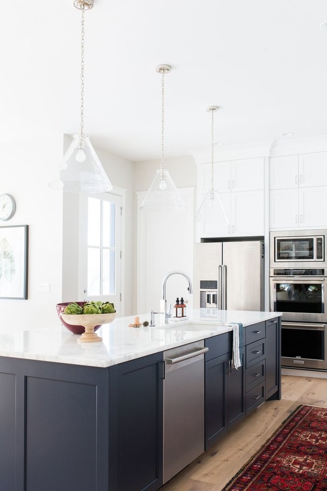 Inspiration for a mid-sized coastal galley light wood floor eat-in kitchen remodel in Salt Lake City with a drop-in sink, white cabinets, white backsplash, subway tile backsplash and an island