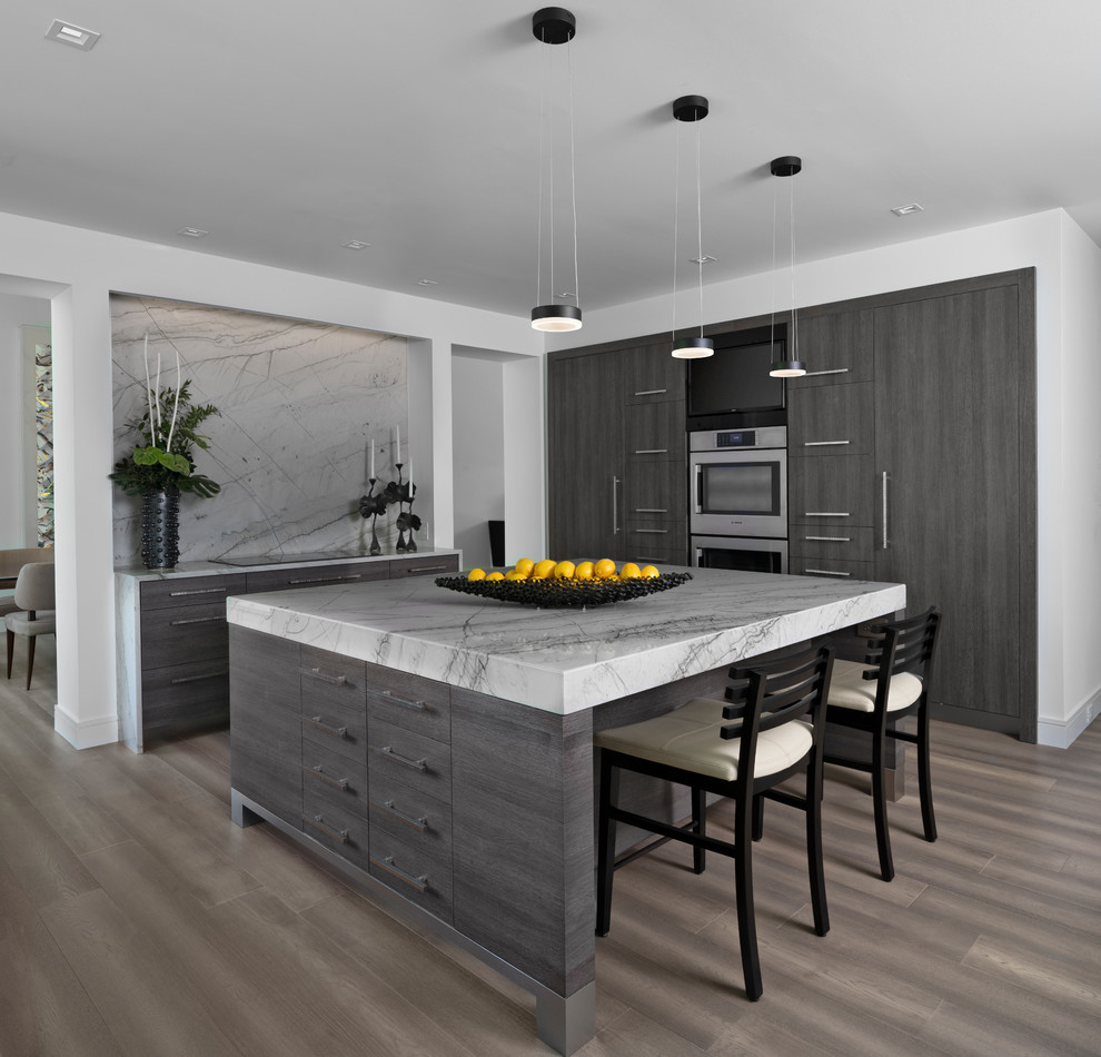 Trendy brown floor kitchen photo in Detroit with flat-panel cabinets, dark wood cabinets, gray backsplash, stone slab backsplash, stainless steel appliances, an island and gray countertops