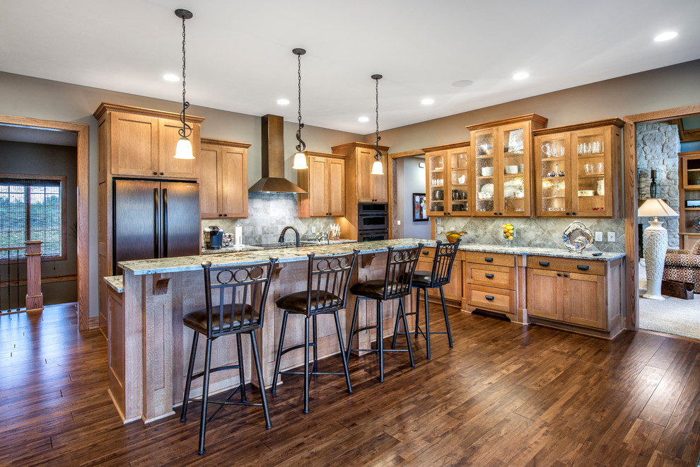 Arts and crafts l-shaped dark wood floor eat-in kitchen photo in Omaha with shaker cabinets, medium tone wood cabinets, gray backsplash, stone tile backsplash, stainless steel appliances, an undermount sink, granite countertops and an island