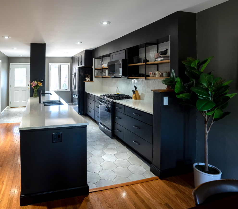 Eat-in kitchen - mid-sized contemporary galley ceramic tile and gray floor eat-in kitchen idea in Other with a single-bowl sink, shaker cabinets, black cabinets, quartz countertops, white backsplash, ceramic backsplash, stainless steel appliances, an island and white countertops