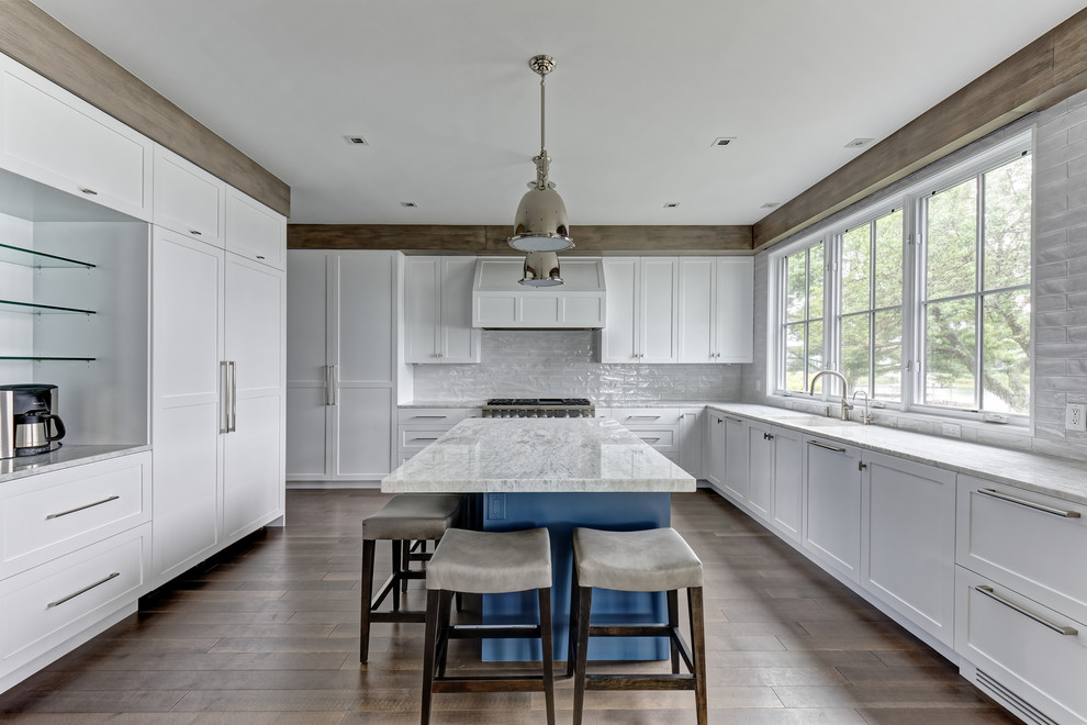 Klassisk inredning av ett stort grå grått kök, med en nedsänkt diskho, släta luckor, vita skåp, granitbänkskiva, vitt stänkskydd, stänkskydd i keramik, rostfria vitvaror, målat trägolv, en köksö och brunt golv