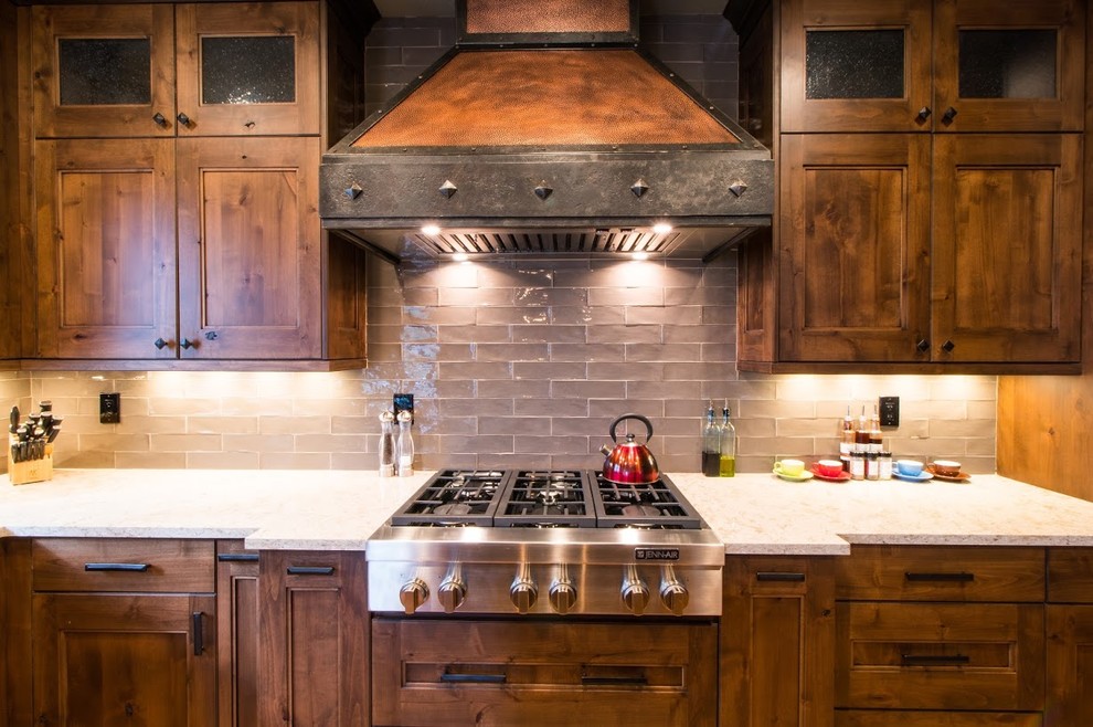 Exempel på ett stort rustikt beige beige kök, med en rustik diskho, luckor med infälld panel, skåp i mellenmörkt trä, bänkskiva i kvarts, grått stänkskydd, stänkskydd i porslinskakel, rostfria vitvaror, mellanmörkt trägolv, en köksö och brunt golv