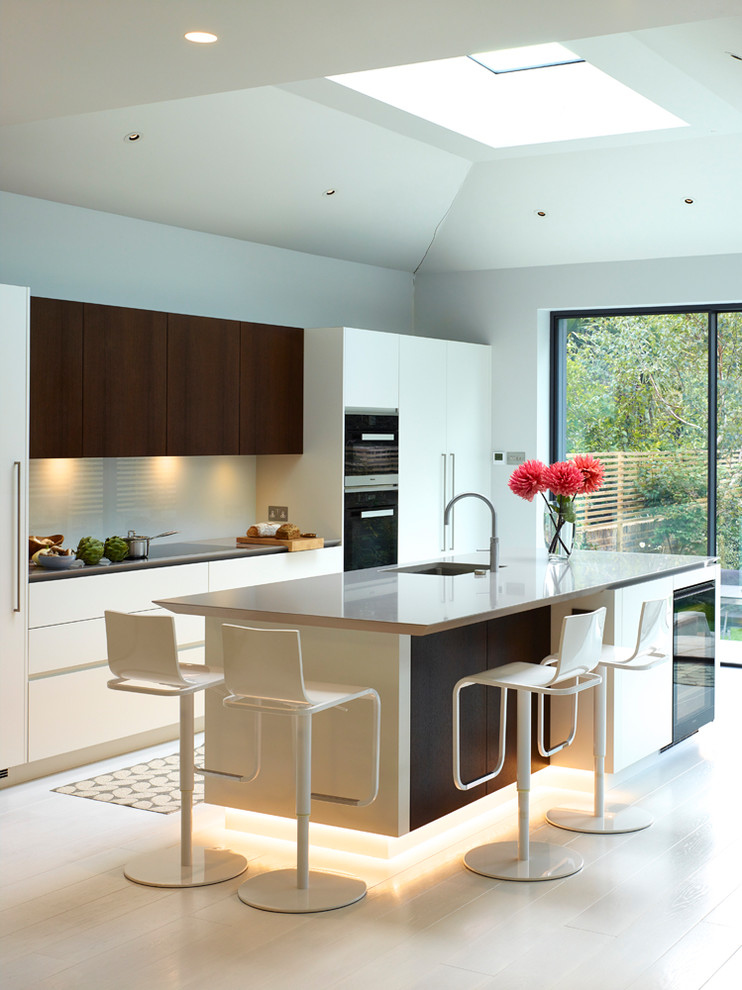 Medium sized contemporary single-wall kitchen/diner in London with flat-panel cabinets, composite countertops, glass sheet splashback, painted wood flooring, an island, white floors and beige worktops.