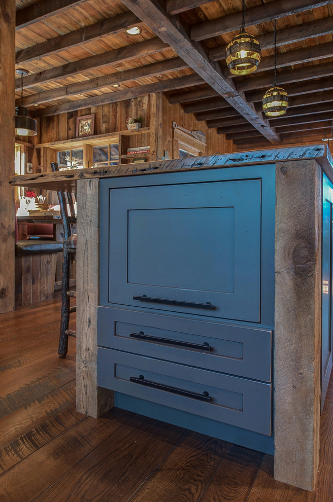 Aménagement d'une grande cuisine américaine montagne en bois vieilli avec un placard à porte plane, un plan de travail en bois, un électroménager en acier inoxydable et îlot.