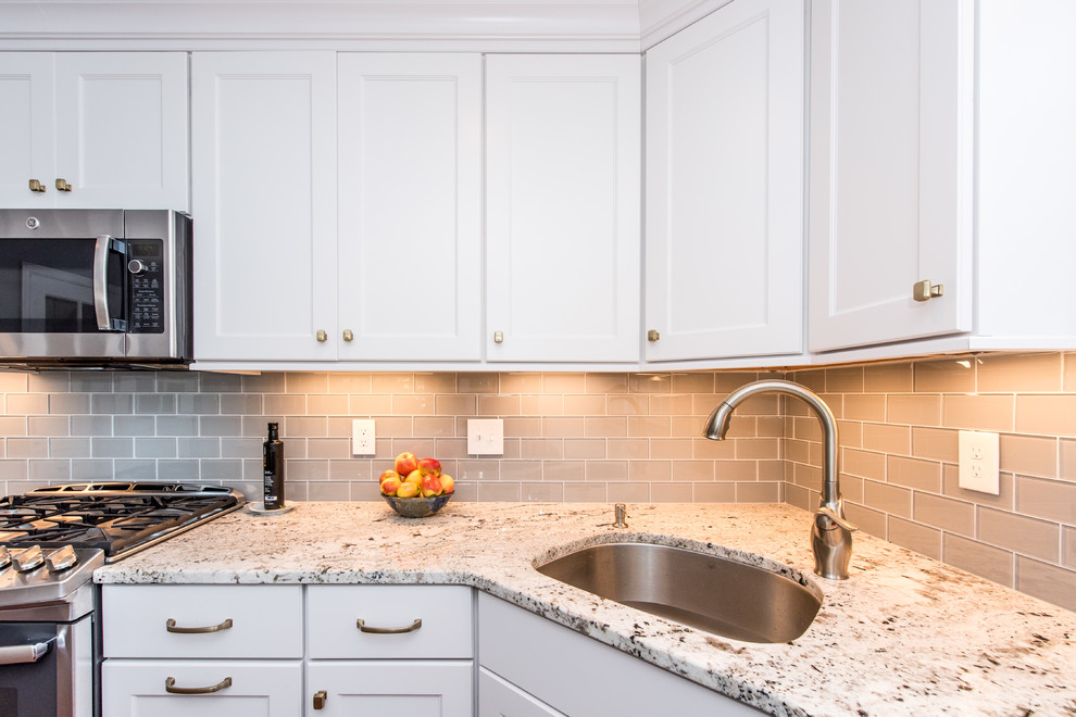 Inspiration for a mid-sized transitional l-shaped laminate floor and brown floor eat-in kitchen remodel in DC Metro with an undermount sink, shaker cabinets, granite countertops, blue backsplash, glass tile backsplash, stainless steel appliances, an island and white cabinets