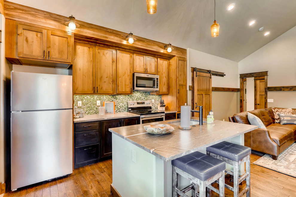 Foto på ett litet rustikt grå linjärt kök med öppen planlösning, med en undermonterad diskho, skåp i shakerstil, skåp i mellenmörkt trä, bänkskiva i kvarts, grönt stänkskydd, stänkskydd i glaskakel, rostfria vitvaror, mellanmörkt trägolv, en köksö och brunt golv