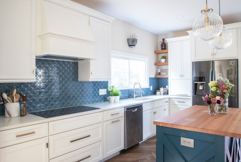 Foto de cocina tradicional renovada con fregadero bajoencimera, armarios estilo shaker, puertas de armario blancas, encimera de cuarzo compacto, salpicadero azul, salpicadero de azulejos de cerámica, electrodomésticos negros, suelo vinílico, una isla y encimeras blancas