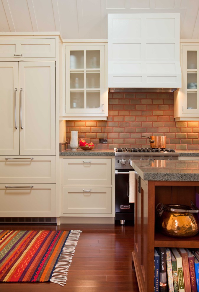 Enclosed kitchen - large traditional single-wall dark wood floor and brown floor enclosed kitchen idea in San Diego with glass-front cabinets, granite countertops, beige cabinets, red backsplash, brick backsplash, stainless steel appliances and an island