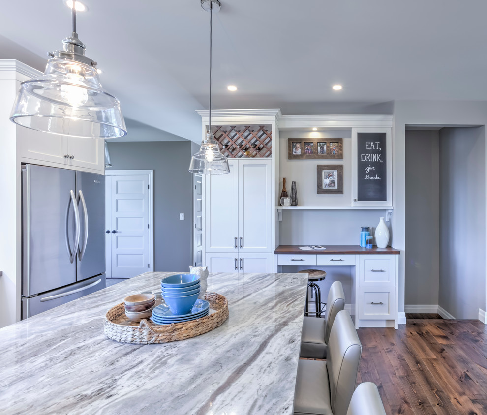Large classic kitchen/diner in Toronto with white cabinets, engineered stone countertops, stainless steel appliances, an island, shaker cabinets, medium hardwood flooring and brown floors.