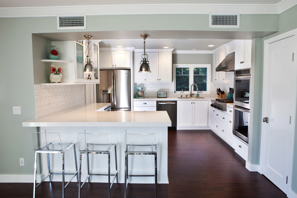 Klassische Küche mit Schrankfronten mit vertiefter Füllung, weißen Schränken, Küchenrückwand in Weiß, Rückwand aus Metrofliesen, Küchengeräten aus Edelstahl und Halbinsel in Orange County