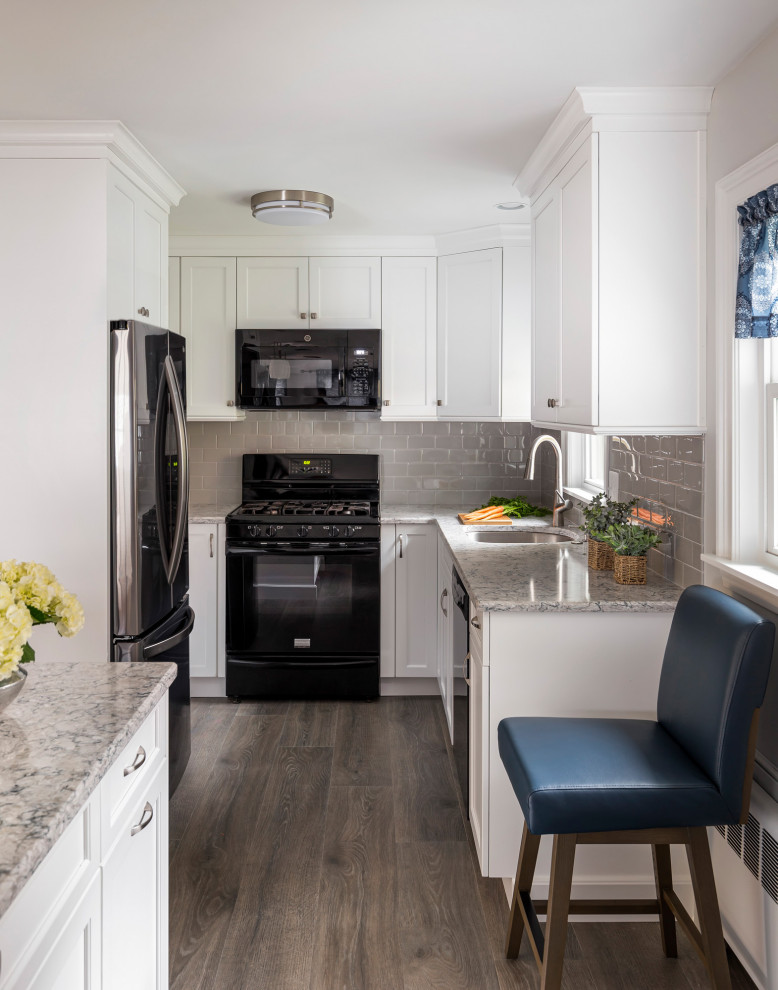 Eat-in kitchen - small transitional u-shaped laminate floor and brown floor eat-in kitchen idea in Boston with an undermount sink, shaker cabinets, white cabinets, quartz countertops, gray backsplash, subway tile backsplash, black appliances, an island and multicolored countertops
