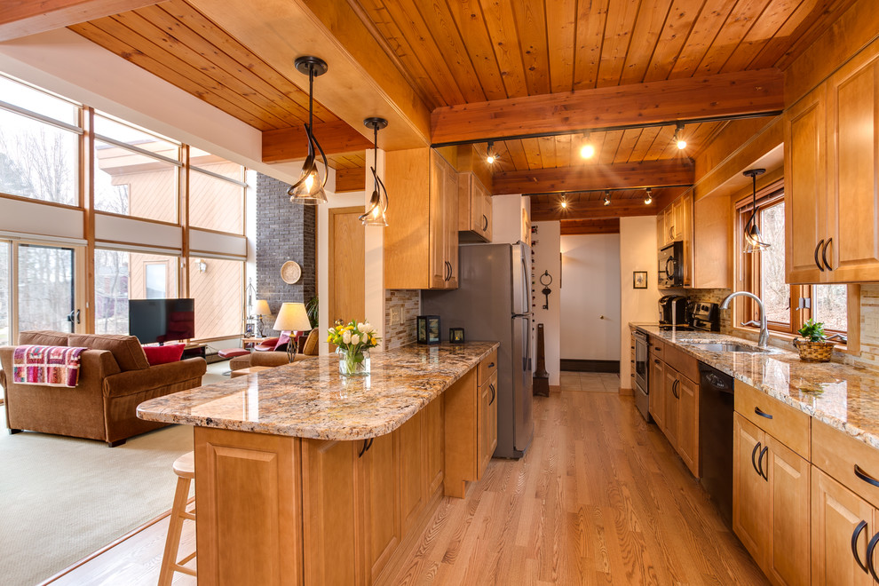 Foto på ett litet vintage kök, med en undermonterad diskho, luckor med upphöjd panel, skåp i mellenmörkt trä, granitbänkskiva, gult stänkskydd, stänkskydd i glaskakel, svarta vitvaror, laminatgolv och en halv köksö
