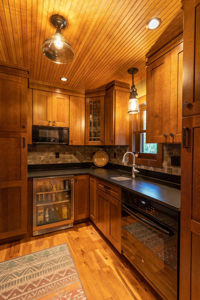 Example of a large mountain style l-shaped medium tone wood floor, brown floor and wood ceiling open concept kitchen design in Burlington with an undermount sink, recessed-panel cabinets, medium tone wood cabinets, gray backsplash, stainless steel appliances, an island and gray countertops