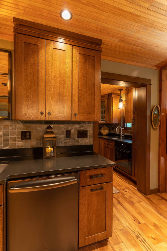 Rustik inredning av ett stort grå grått kök, med en undermonterad diskho, luckor med infälld panel, skåp i mellenmörkt trä, grått stänkskydd, rostfria vitvaror, mellanmörkt trägolv, en köksö och brunt golv
