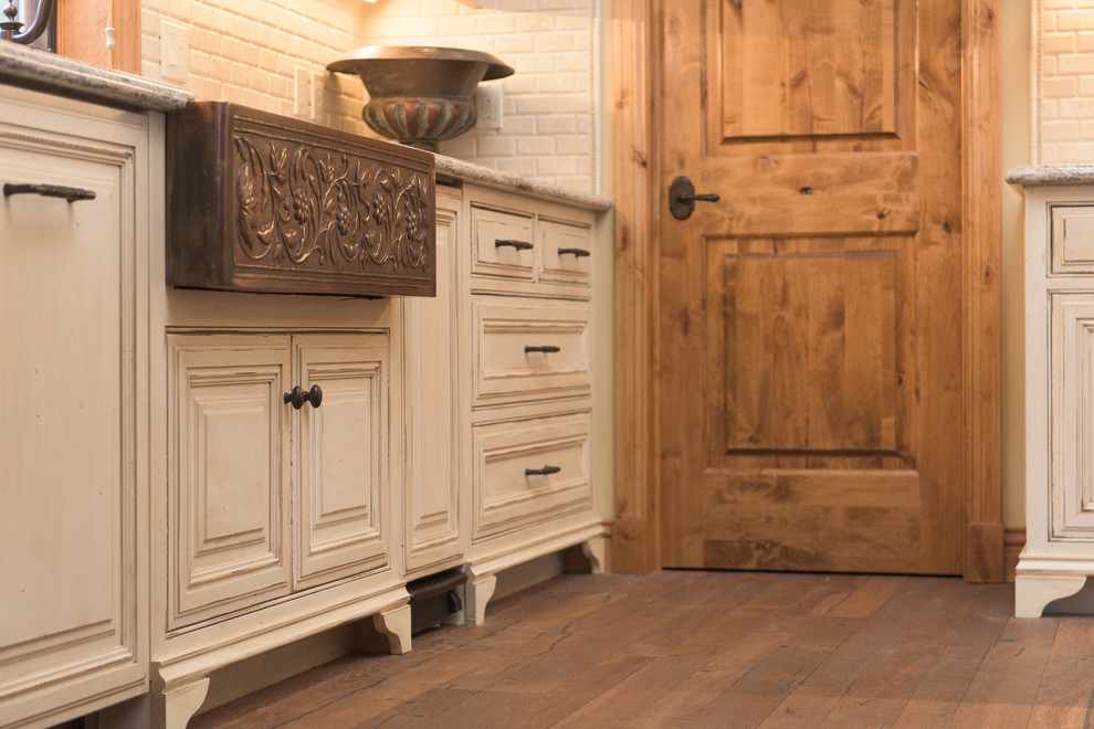 Exempel på ett stort rustikt kök, med en rustik diskho, luckor med profilerade fronter, vita skåp, granitbänkskiva, vitt stänkskydd, stänkskydd i stenkakel, rostfria vitvaror, mellanmörkt trägolv och en köksö