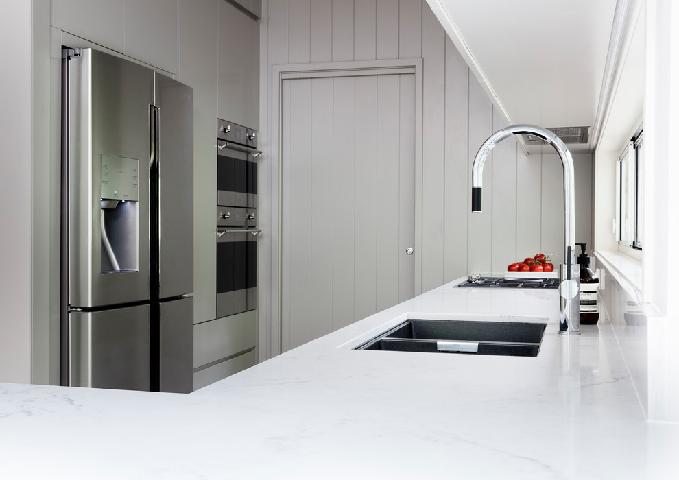 Large retro galley kitchen pantry in Sydney with a submerged sink, flat-panel cabinets, grey cabinets, engineered stone countertops, window splashback, stainless steel appliances, light hardwood flooring, a breakfast bar, beige floors and multicoloured worktops.