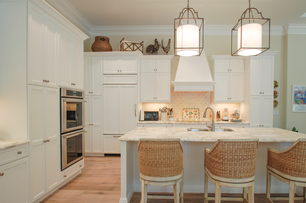 Foto de cocina tradicional con puertas de armario blancas, salpicadero beige, salpicadero de azulejos tipo metro y electrodomésticos de acero inoxidable