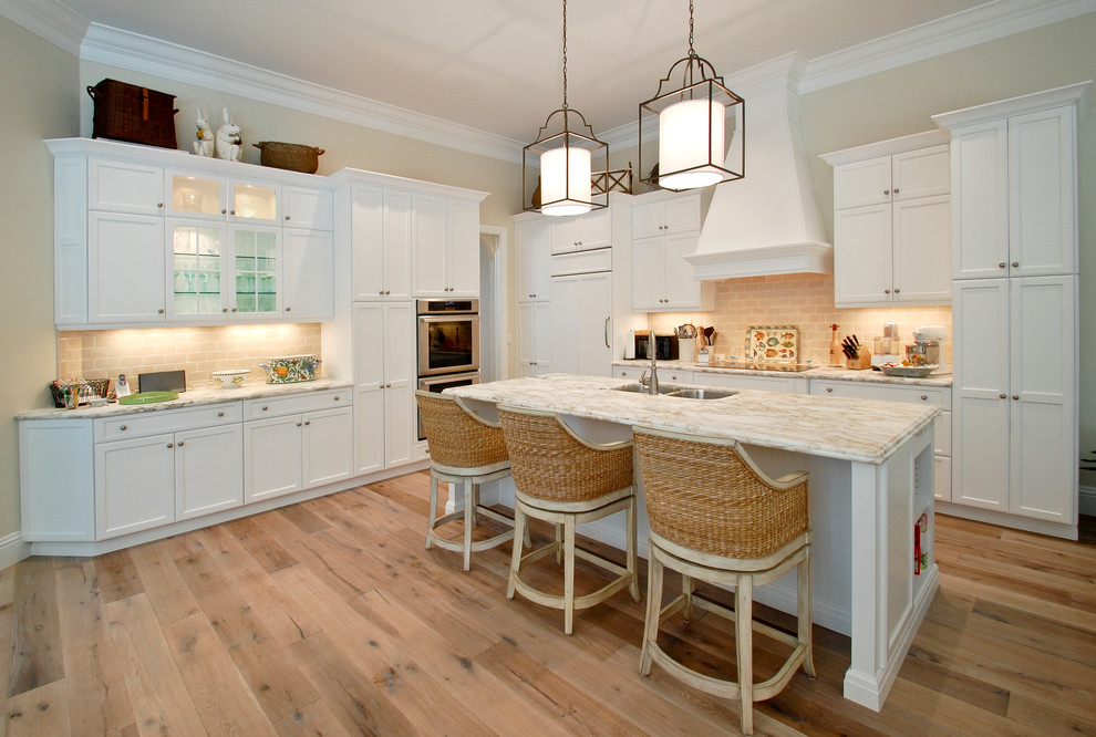 Photo of a classic l-shaped kitchen in Miami with a double-bowl sink, shaker cabinets, white cabinets, beige splashback and integrated appliances.