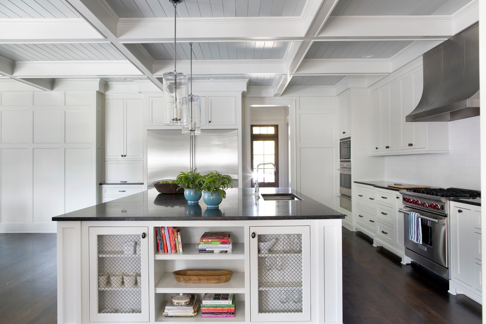Design ideas for a traditional l-shaped kitchen in Atlanta with a submerged sink, shaker cabinets, white cabinets, white splashback, metro tiled splashback, stainless steel appliances, dark hardwood flooring and an island.