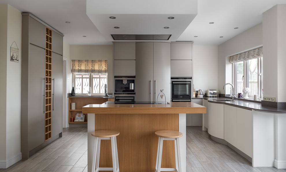 Medium sized contemporary u-shaped kitchen/diner in Other with flat-panel cabinets, grey cabinets, granite worktops, integrated appliances, medium hardwood flooring, an island and grey floors.