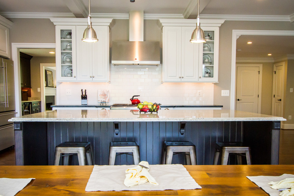 Example of a mid-sized classic galley medium tone wood floor and brown floor eat-in kitchen design in Philadelphia with raised-panel cabinets, white cabinets, white backsplash, subway tile backsplash, stainless steel appliances and an island