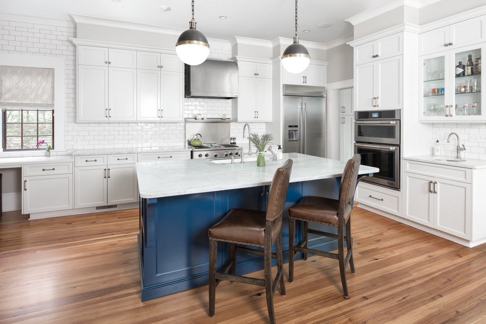 Inspiration for a large transitional medium tone wood floor kitchen remodel in Charlotte with shaker cabinets, quartz countertops, white backsplash, stainless steel appliances, an island, white countertops, white cabinets and subway tile backsplash
