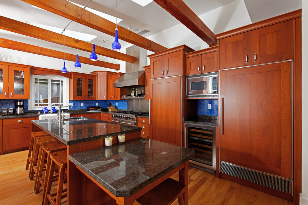 Ejemplo de cocina de estilo americano con fregadero bajoencimera, puertas de armario de madera oscura, salpicadero azul y salpicadero con mosaicos de azulejos