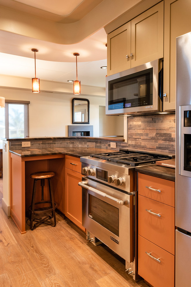 Foto på ett mellanstort amerikanskt flerfärgad kök, med en nedsänkt diskho, skåp i shakerstil, orange skåp, granitbänkskiva, flerfärgad stänkskydd, stänkskydd i stenkakel, rostfria vitvaror, ljust trägolv, en halv köksö och brunt golv