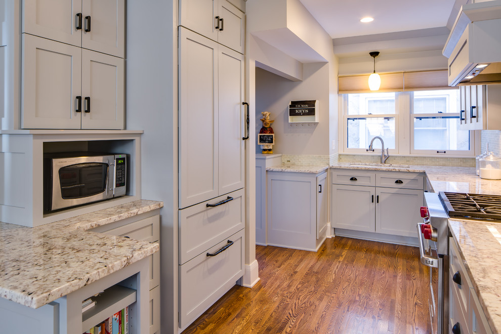 Example of a small trendy galley medium tone wood floor kitchen pantry design in Minneapolis with an undermount sink, shaker cabinets, gray cabinets, granite countertops, white backsplash, mosaic tile backsplash, paneled appliances and a peninsula