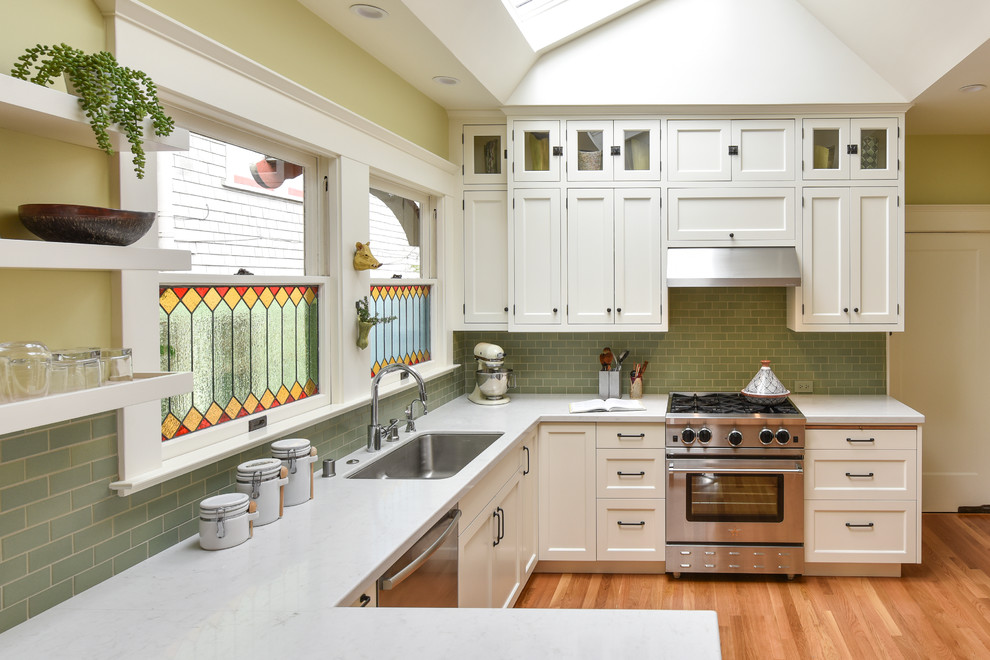 Inspiration for a medium sized traditional u-shaped kitchen/diner in San Francisco with a single-bowl sink, shaker cabinets, white cabinets, engineered stone countertops, green splashback, ceramic splashback, stainless steel appliances, medium hardwood flooring and a breakfast bar.