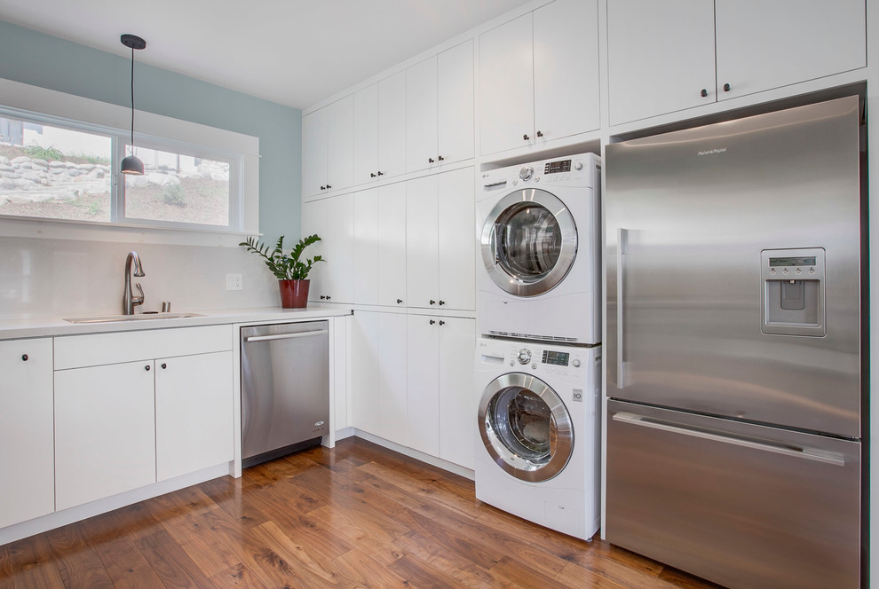 ロサンゼルスにあるトランジショナルスタイルのおしゃれなL型キッチン (アンダーカウンターシンク、フラットパネル扉のキャビネット、白いキャビネット、シルバーの調理設備、濃色無垢フローリング) の写真