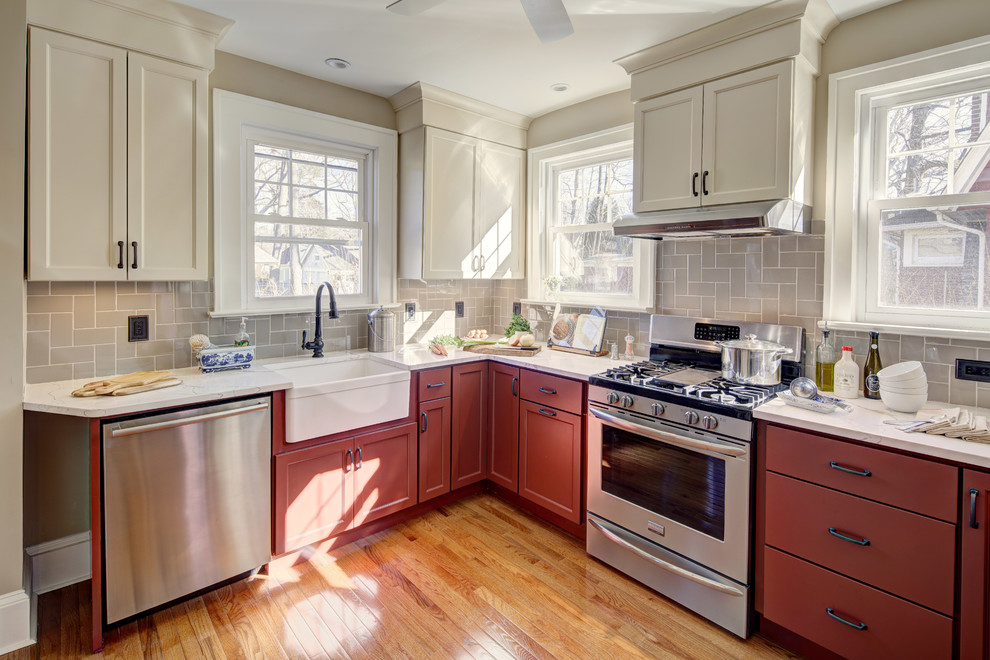 Example of a mid-sized arts and crafts u-shaped light wood floor and brown floor enclosed kitchen design in New York with a farmhouse sink, shaker cabinets, red cabinets, quartz countertops, ceramic backsplash, stainless steel appliances and no island