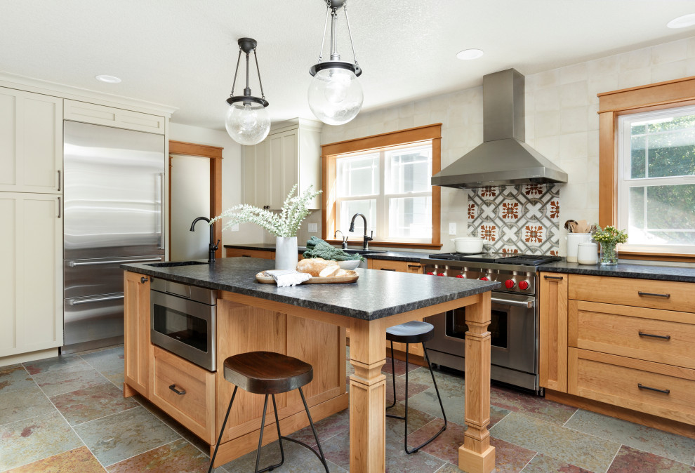 Exempel på ett avskilt, mellanstort lantligt svart svart u-kök, med en rustik diskho, skåp i shakerstil, skåp i mellenmörkt trä, granitbänkskiva, vitt stänkskydd, stänkskydd i keramik, rostfria vitvaror, skiffergolv, en köksö och flerfärgat golv