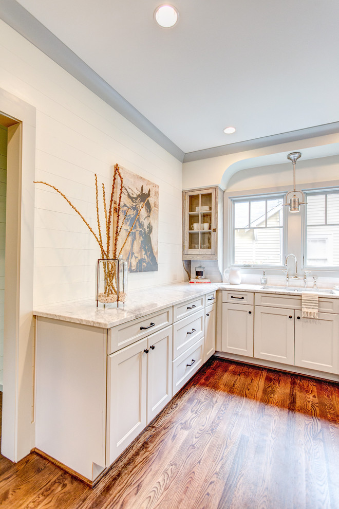 Amerikansk inredning av ett mellanstort kök, med en undermonterad diskho, släta luckor, grå skåp, marmorbänkskiva, vitt stänkskydd, stänkskydd i keramik, rostfria vitvaror, mellanmörkt trägolv och en halv köksö