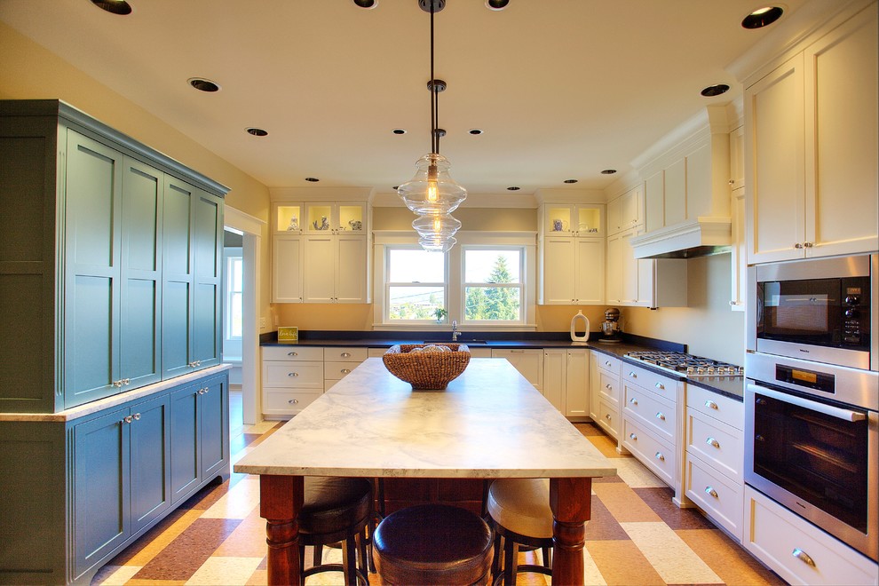 Example of an arts and crafts linoleum floor kitchen design in Seattle with an island, shaker cabinets, white cabinets, marble countertops, stainless steel appliances and an undermount sink