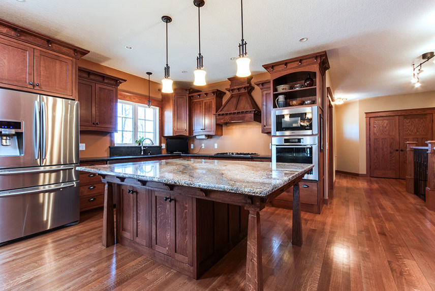 Inspiration for a mid-sized craftsman l-shaped medium tone wood floor open concept kitchen remodel in Chicago with shaker cabinets, medium tone wood cabinets, laminate countertops, stainless steel appliances and an island