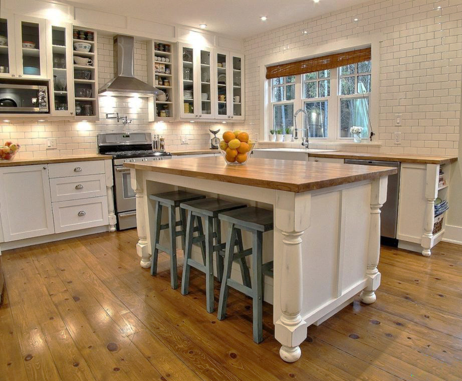 Inspiration for a mid-sized timeless u-shaped medium tone wood floor eat-in kitchen remodel in Ottawa with a farmhouse sink, distressed cabinets, wood countertops, white backsplash, subway tile backsplash, stainless steel appliances and an island