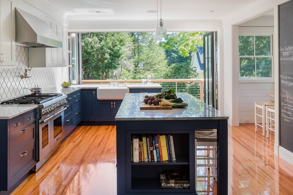 Idéer för ett lantligt kök, med en rustik diskho, skåp i shakerstil, blå skåp, granitbänkskiva, fönster som stänkskydd, rostfria vitvaror, mellanmörkt trägolv, en köksö och brunt golv