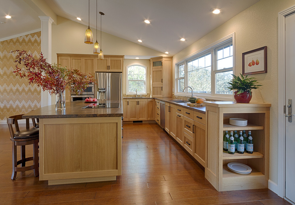 Example of an arts and crafts l-shaped medium tone wood floor kitchen design in San Francisco with shaker cabinets, light wood cabinets, solid surface countertops, stainless steel appliances and an island