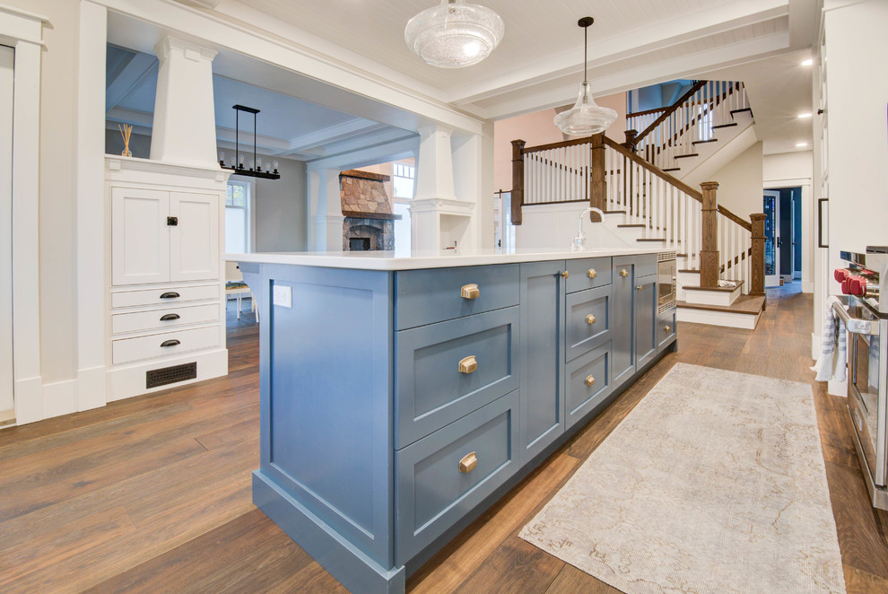 Mid-sized arts and crafts single-wall medium tone wood floor and brown floor enclosed kitchen photo in Calgary with shaker cabinets, blue cabinets, quartz countertops, an island, white countertops, a farmhouse sink and stainless steel appliances